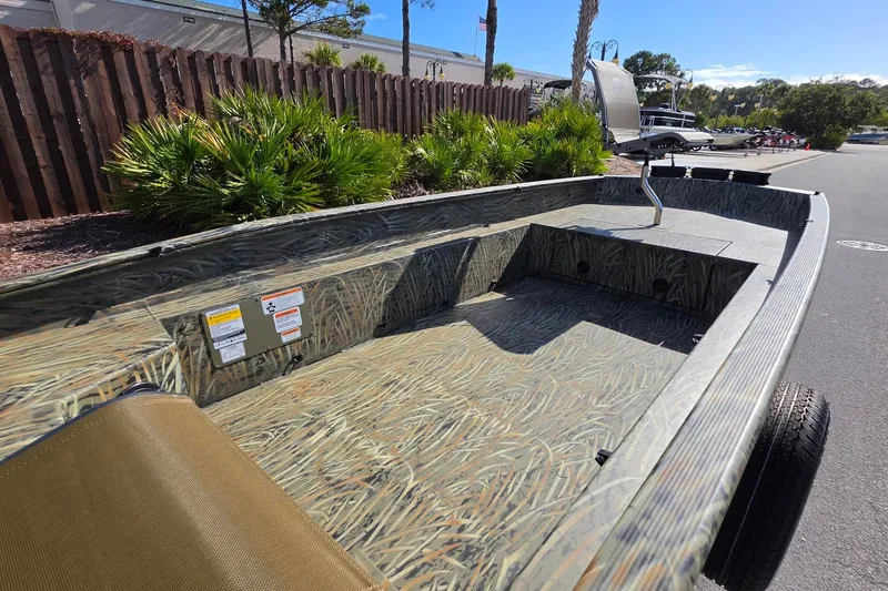 Slide: The Image of 2027 Tracker Grizzly 1650 T Prairie Wings Edition boat with camouflage design, parked outdoors. - 15