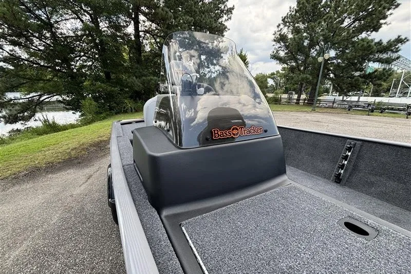 Slide: The Image of 2027 Tracker Bass Tracker Classic Limited boat with windshield, parked near trees and water. - 12