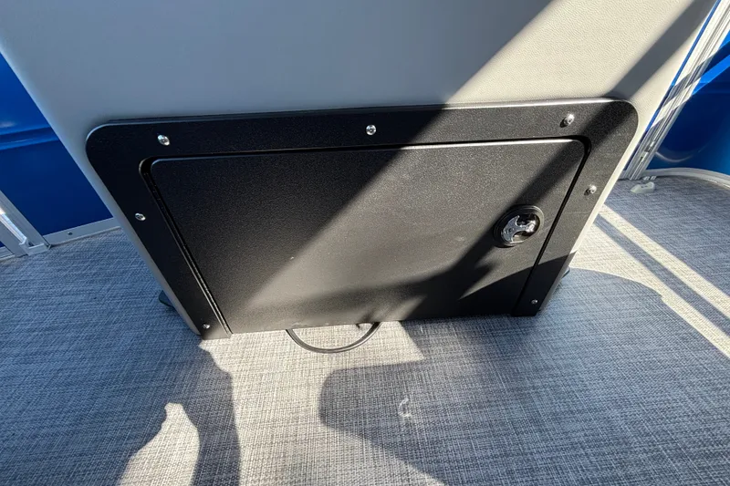 Slide: The Image of 2027 Sun Tracker SportFish 22 DLX storage compartment with lock on carpeted floor. - 35