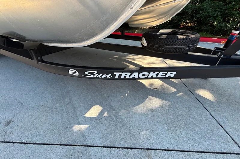 Slide: The Image of 2027 Sun Tracker SportFish 22 DLX trailer with spare tire on concrete surface. - 60