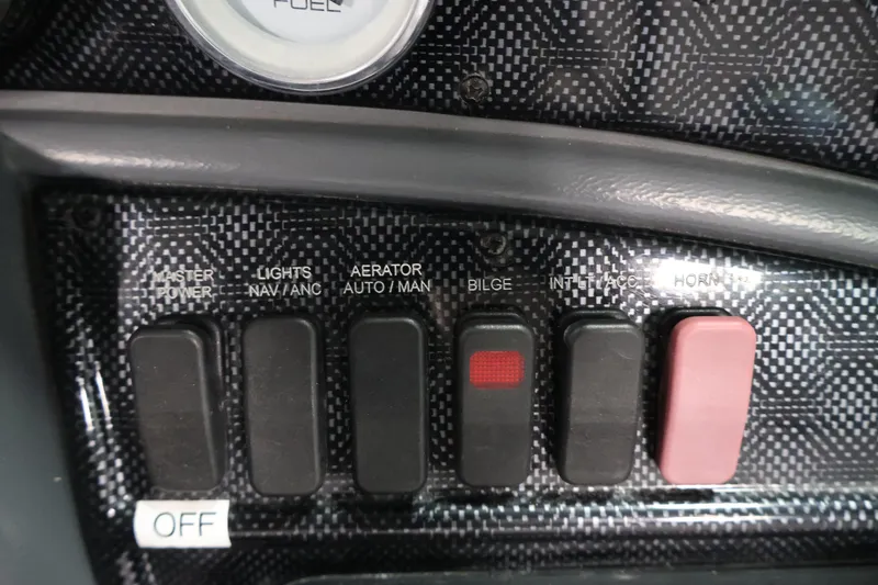 Slide: The Image of Dashboard controls of a 2013 Lund 1750 Tyee boat, featuring various switches. - 23