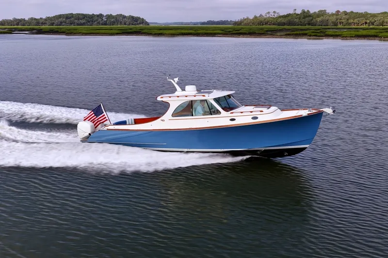 The Image of 2022 Hinckley 35 boat cruising on a calm river with lush green banks. - 0