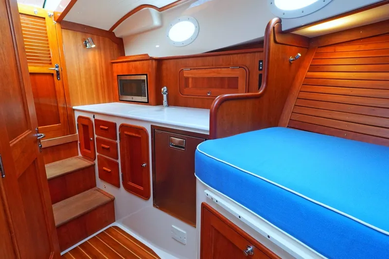 Slide: The Image of Interior of 2022 Hinckley 35 yacht with wooden cabinetry and blue cushioned seating. - 14