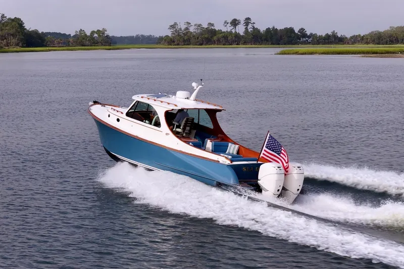 Slide: The Image of 2022 Hinckley 35 boat cruising on a serene lake with American flag. - 22