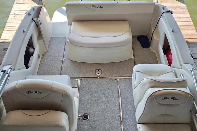 Slide: The Image of 2000 Sea Ray 245 Weekender boat interior with beige seating and carpeted floor. - 9