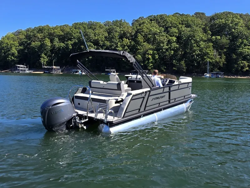 Slide: The Image of A 2027 Starcraft EX 20 Q DH pontoon boat on a calm lake with a wooded shoreline. - 5