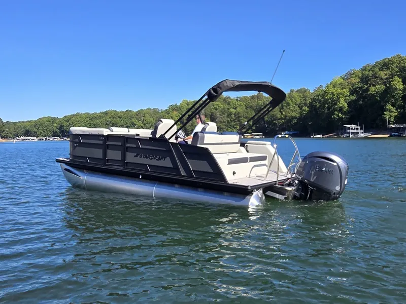Slide: The Image of A Starcraft EX 20 Q DH pontoon boat on a calm lake with a wooded shoreline in the background. - 34