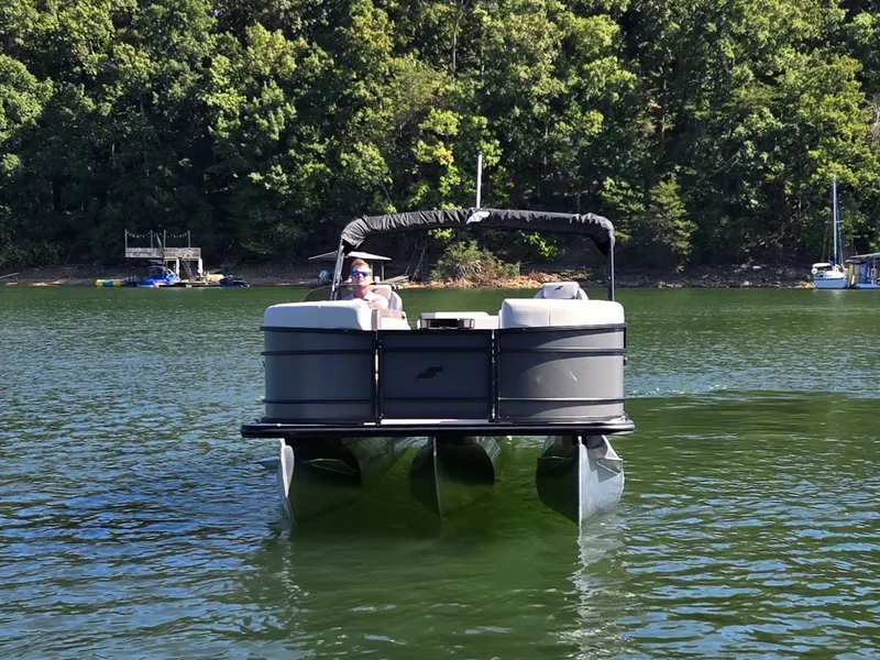 Slide: The Image of A 2027 Starcraft EX 20 Q DH pontoon boat on a calm lake with a wooded shoreline. - 2