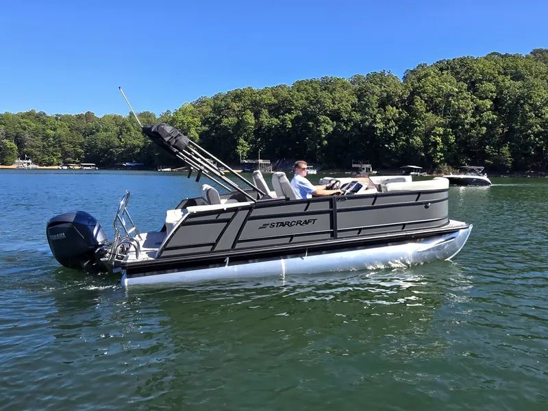 Slide: The Image of A 2027 Starcraft EX 20 Q DH pontoon boat cruising on a calm lake with wooded shoreline. - 32