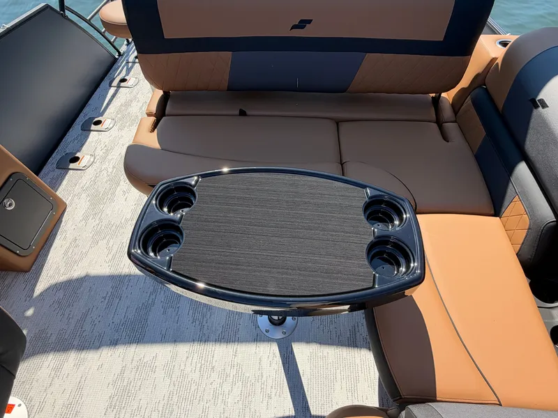 Slide: The Image of The image shows the seating area of a 2027 Starcraft EXS 3 DL boat with a table and cup holders. - 18
