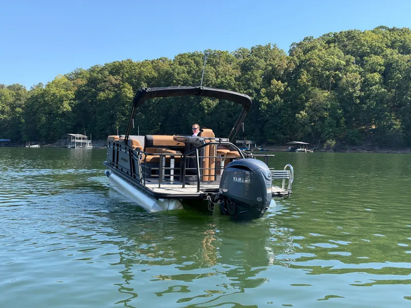 Slide: The Image of A 2027 Starcraft EXS 3 DL pontoon boat on a calm lake with a wooded shoreline. - 43