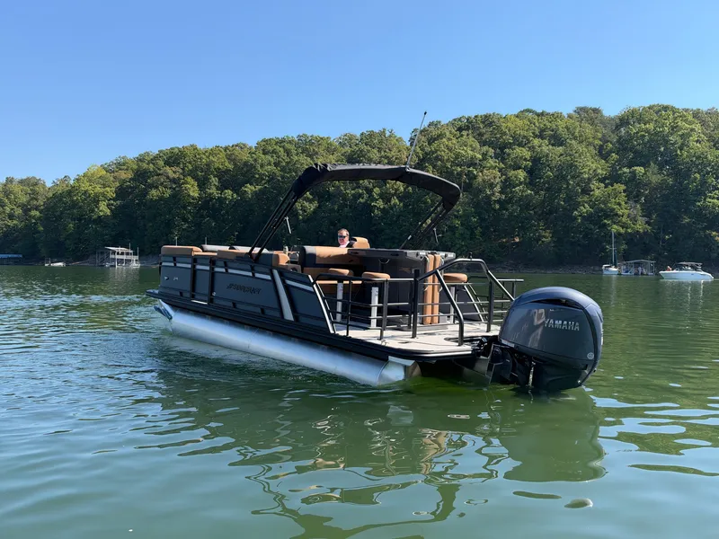 Slide: The Image of The image shows a 2027 Starcraft EXS 3 DL pontoon boat on a calm lake. - 42