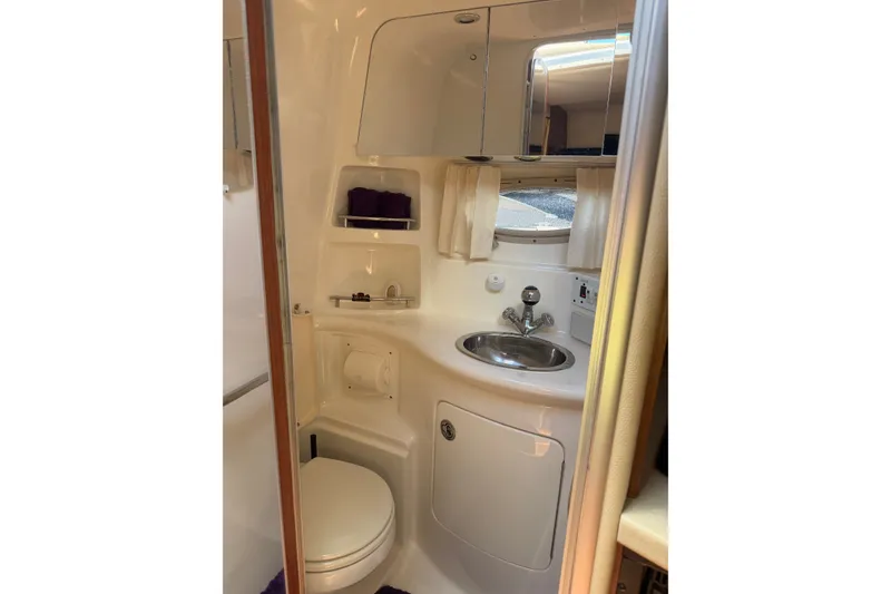Slide: The Image of 2004 Chaparral Signature 310 boat bathroom with sink, toilet, and storage shelves. - 15