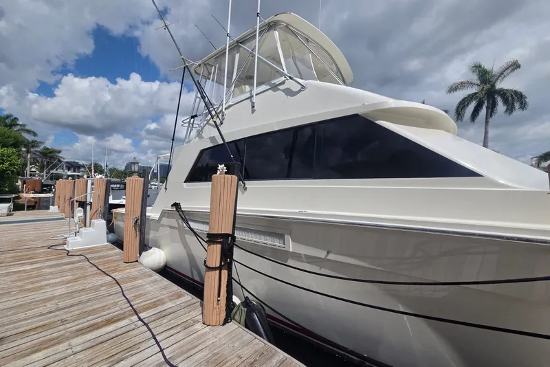 Slide: The Image of 1984 Bertram 54 Convertible yacht docked under a partly cloudy sky. - 112