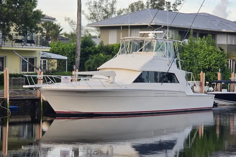 Slide: The Image of 1984 Bertram 54 Convertible yacht docked by waterfront homes. - 21
