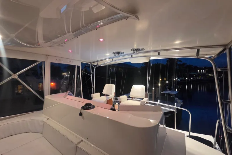 Slide: The Image of Interior of a 1984 Bertram 54 Convertible yacht at night, featuring seating and helm. - 90