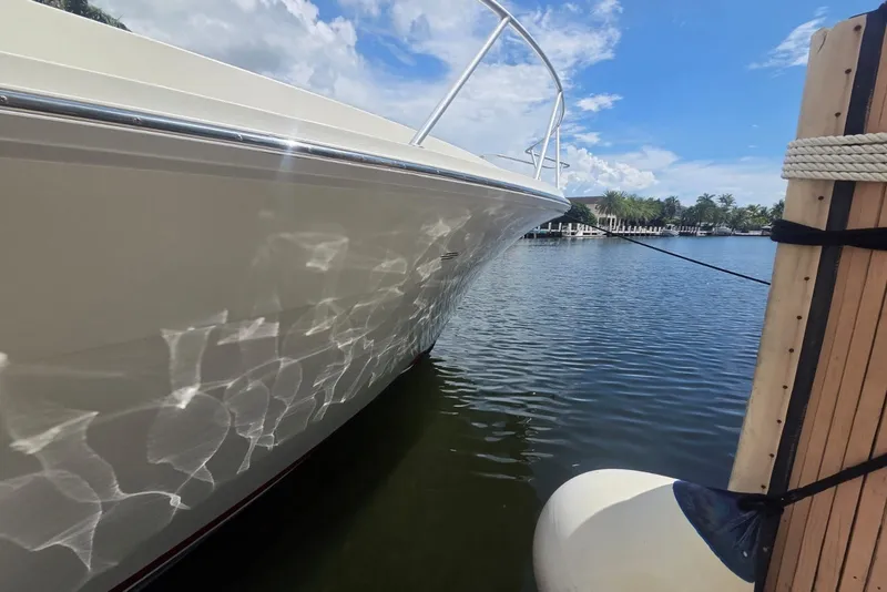 Slide: The Image of 1984 Bertram 54 Convertible yacht docked on a sunny day, reflecting water patterns. - 117