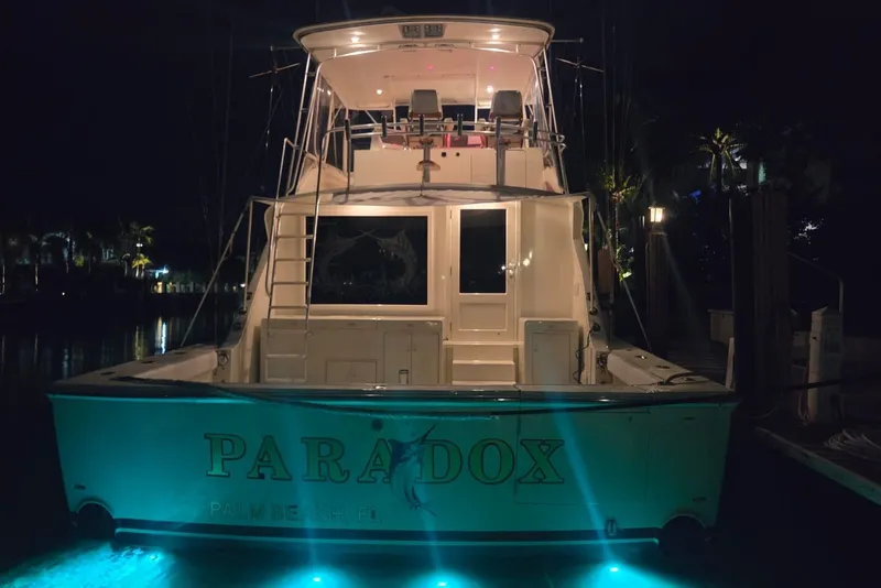 Slide: The Image of 1984 Bertram 54 Convertible yacht docked at night with illuminated water. - 53