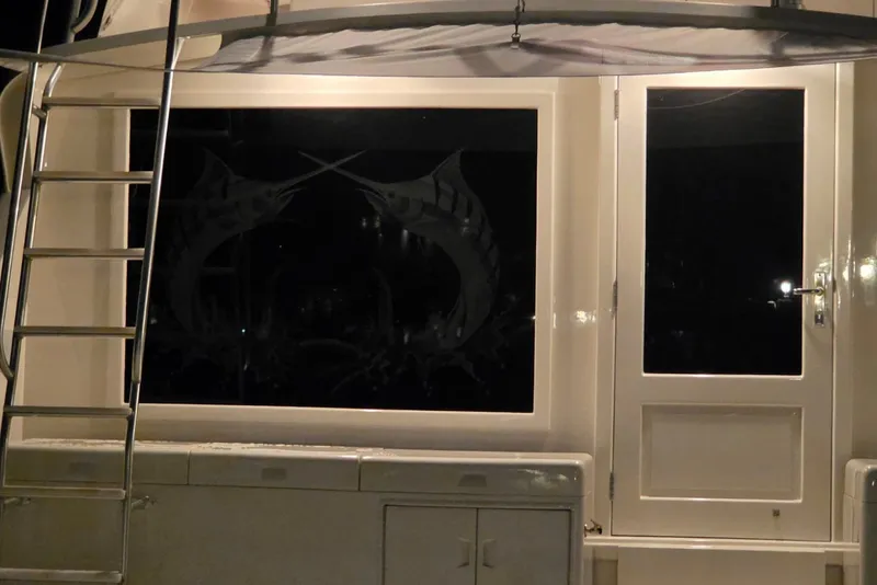 Slide: The Image of 1984 Bertram 54 Convertible yacht with ladder and marlin window design at night. - 109