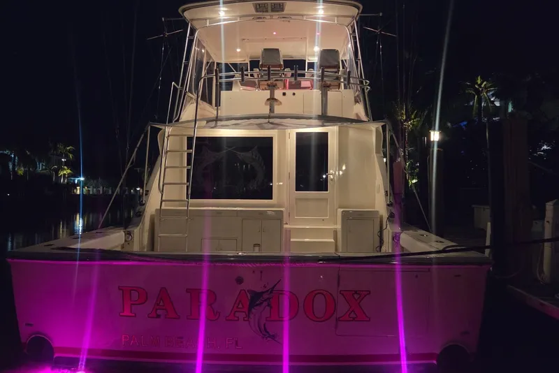 Slide: The Image of 1984 Bertram 54 Convertible yacht with pink lights at night, docked in Palm Beach, FL. - 54