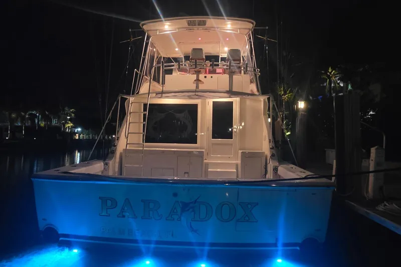 Slide: The Image of 1984 Bertram 54 Convertible yacht "Paradox" docked at night with blue underwater lights. - 65