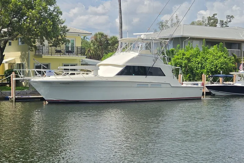 Slide: The Image of 1984 Bertram 54 Convertible yacht docked by waterfront homes. - 116