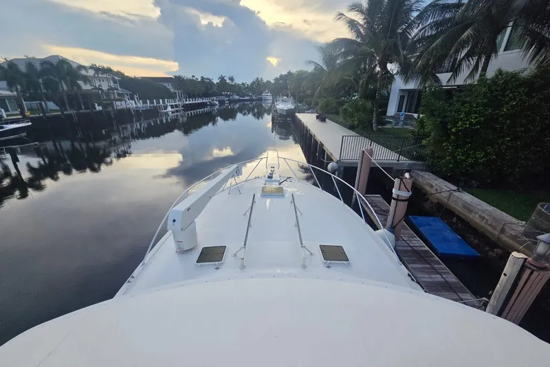 Slide: The Image of Front view of a 1984 Bertram 54 Convertible yacht docked in a serene canal setting. - 31