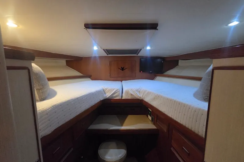 Slide: The Image of Interior cabin of 1984 Bertram 54 Convertible yacht with twin beds and wooden accents. - 106