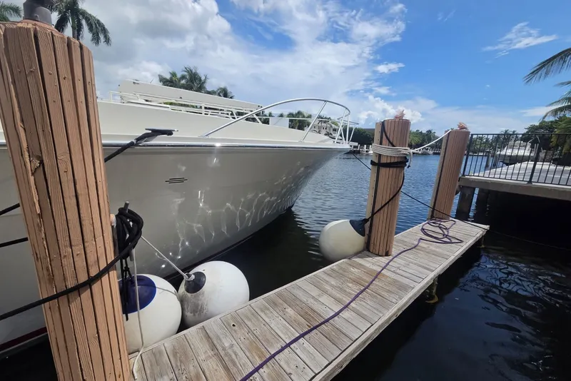 Slide: The Image of 1984 Bertram 54 Convertible yacht docked by wooden pier under blue sky. - 114