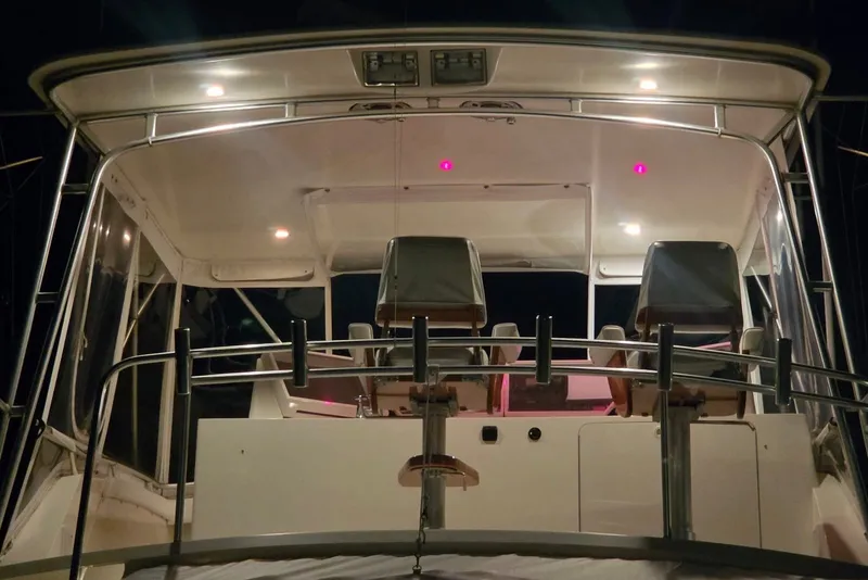 Slide: The Image of 1984 Bertram 54 Convertible yacht cockpit illuminated at night, showcasing seating and controls. - 108
