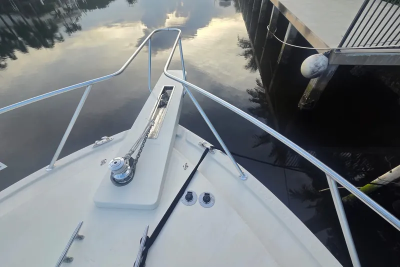 Slide: The Image of Bow of 1984 Bertram 54 Convertible yacht docked by calm water. - 32