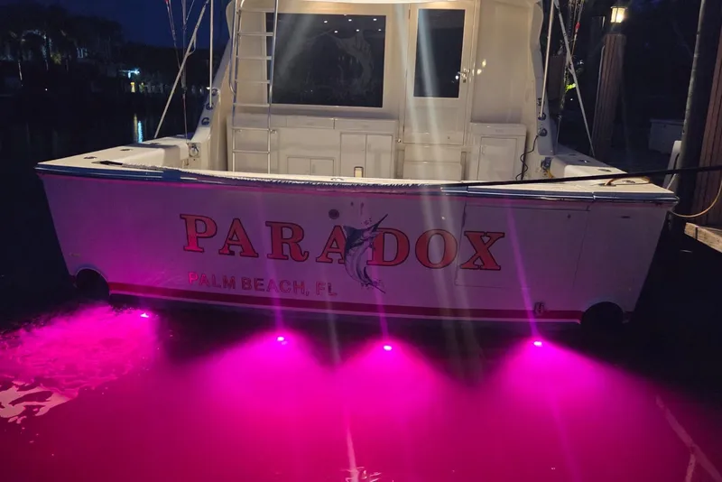Slide: The Image of 1984 Bertram 54 Convertible boat with pink underwater lights at night, docked in Palm Beach. - 97