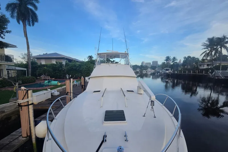 Slide: The Image of 1984 Bertram 54 Convertible yacht docked in a serene waterfront setting. - 33