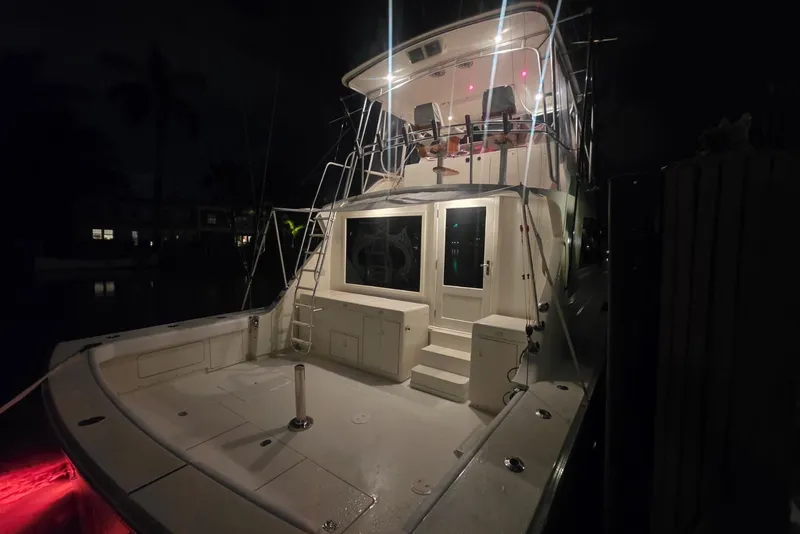 Slide: The Image of 1984 Bertram 54 Convertible yacht illuminated at night, showcasing spacious deck and upper seating. - 52