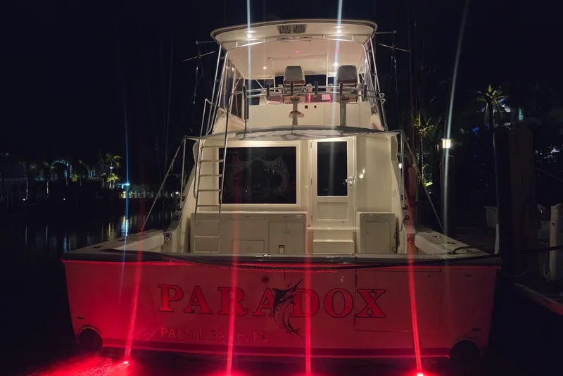 Slide: The Image of 1984 Bertram 54 Convertible yacht "Paradox" docked at night with red lights. - 59