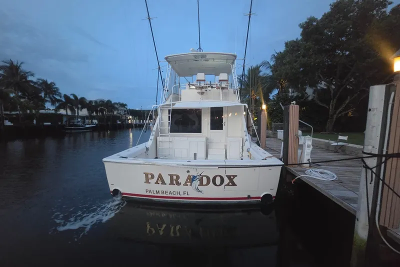 Slide: The Image of 1984 Bertram 54 Convertible yacht docked at Palm Beach marina during twilight. - 84
