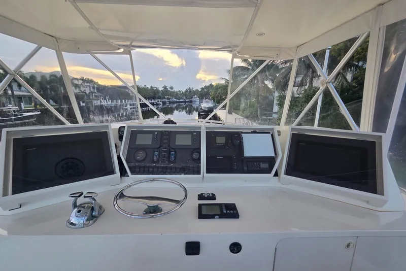 Slide: The Image of Helm of 1984 Bertram 54 Convertible yacht with navigational equipment and scenic waterway view. - 45