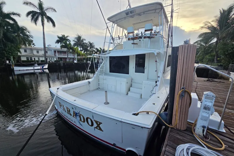Slide: The Image of 1984 Bertram 54 Convertible yacht docked, surrounded by palm trees and waterfront homes. - 28