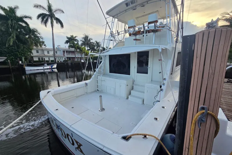 Slide: The Image of 1984 Bertram 54 Convertible yacht docked, surrounded by palm trees and waterfront homes. - 27