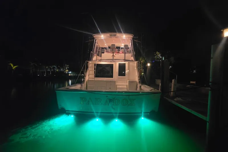 Slide: The Image of 1984 Bertram 54 Convertible yacht illuminated at night with green underwater lights. - 60