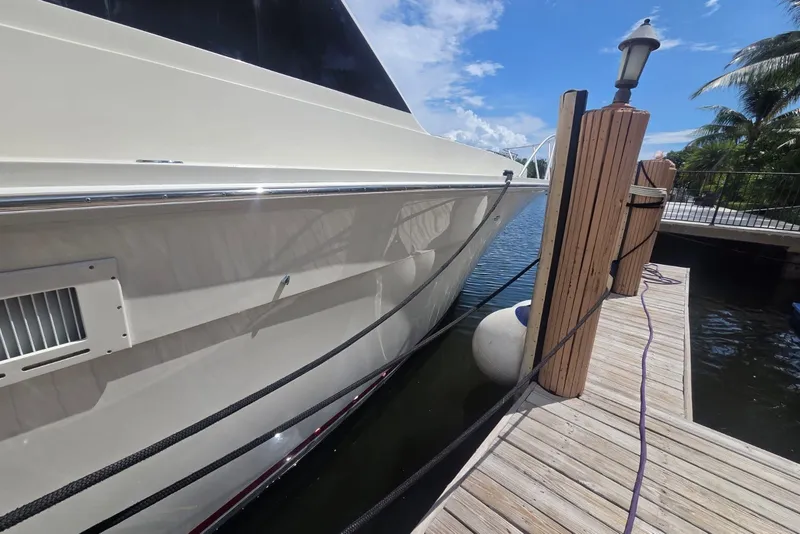 Slide: The Image of 1984 Bertram 54 Convertible yacht docked at a marina under a clear blue sky. - 113