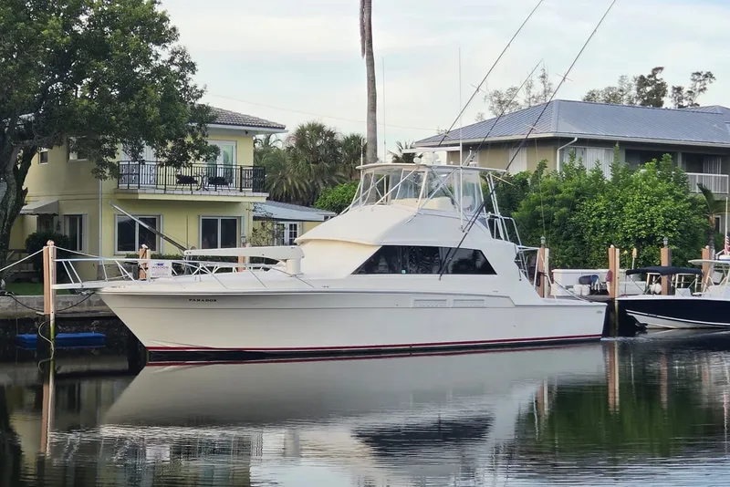 Slide: The Image of 1984 Bertram 54 Convertible yacht docked by waterfront homes. - 24