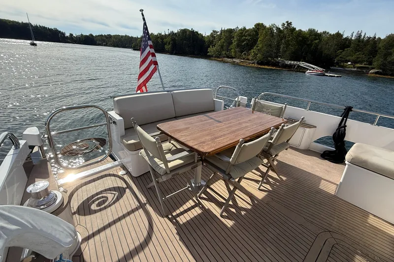 Slide: The Image of 2021 Elling E6 yacht deck with dining area, American flag, and scenic water view. - 14