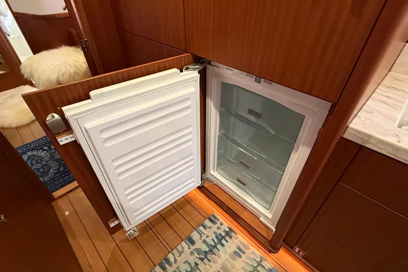 Slide: The Image of Open refrigerator in 2021 Elling E6 yacht interior, featuring wooden cabinetry and a patterned rug. - 54