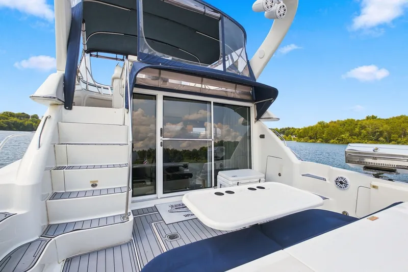 Slide: The Image of 2003 Sea Ray 450 Express Bridge yacht with spacious deck and seating, docked on a serene lake. - 22