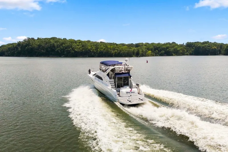 Slide: The Image of 2003 Sea Ray 450 Express Bridge cruising on a serene lake under a clear blue sky. - 24