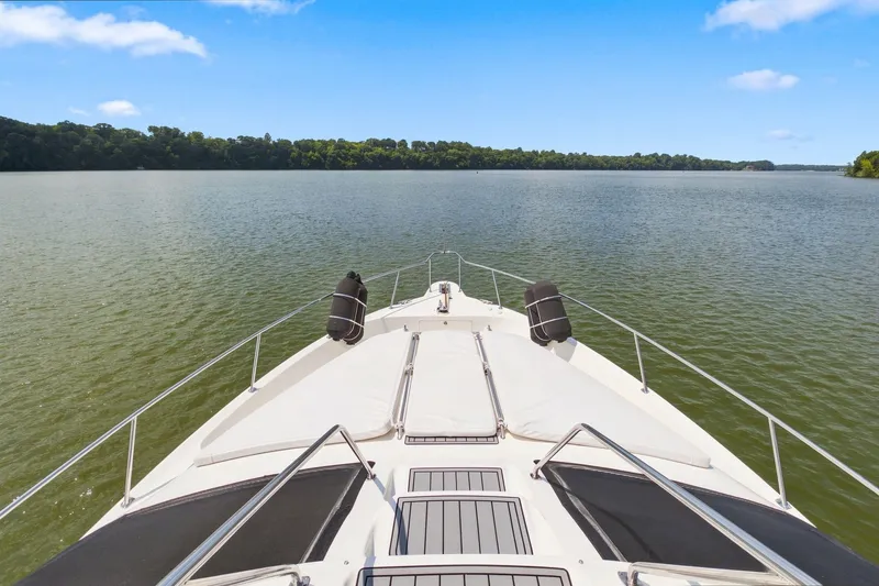 Slide: The Image of Bow view of 2003 Sea Ray 450 Express Bridge on a serene lake. - 20