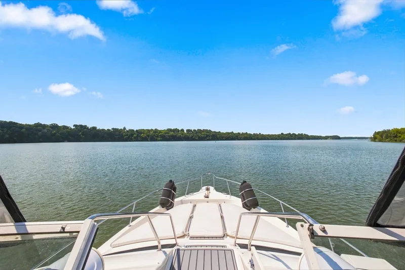 Slide: The Image of 2003 Sea Ray 450 Express Bridge cruising on a serene lake under a clear blue sky. - 19