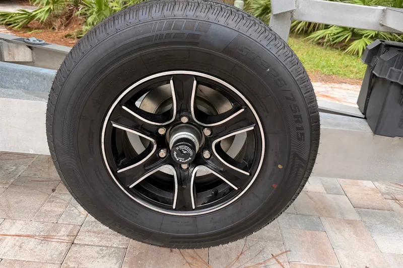 Slide: The Image of Close-up of a 2021 Costa Custom Boats 264HC trailer wheel on a paved surface. - 41