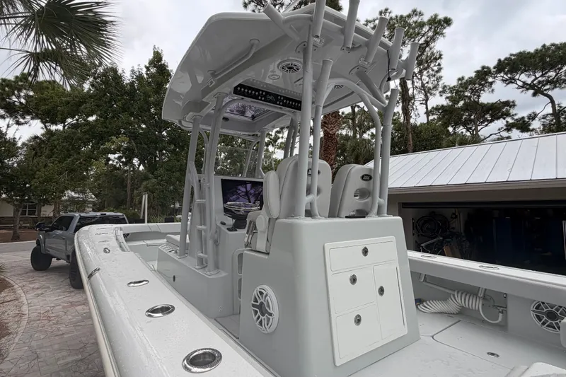 Slide: The Image of 2021 Costa Custom Boats 264HC, sleek design, center console, parked outdoors near trees. - 25
